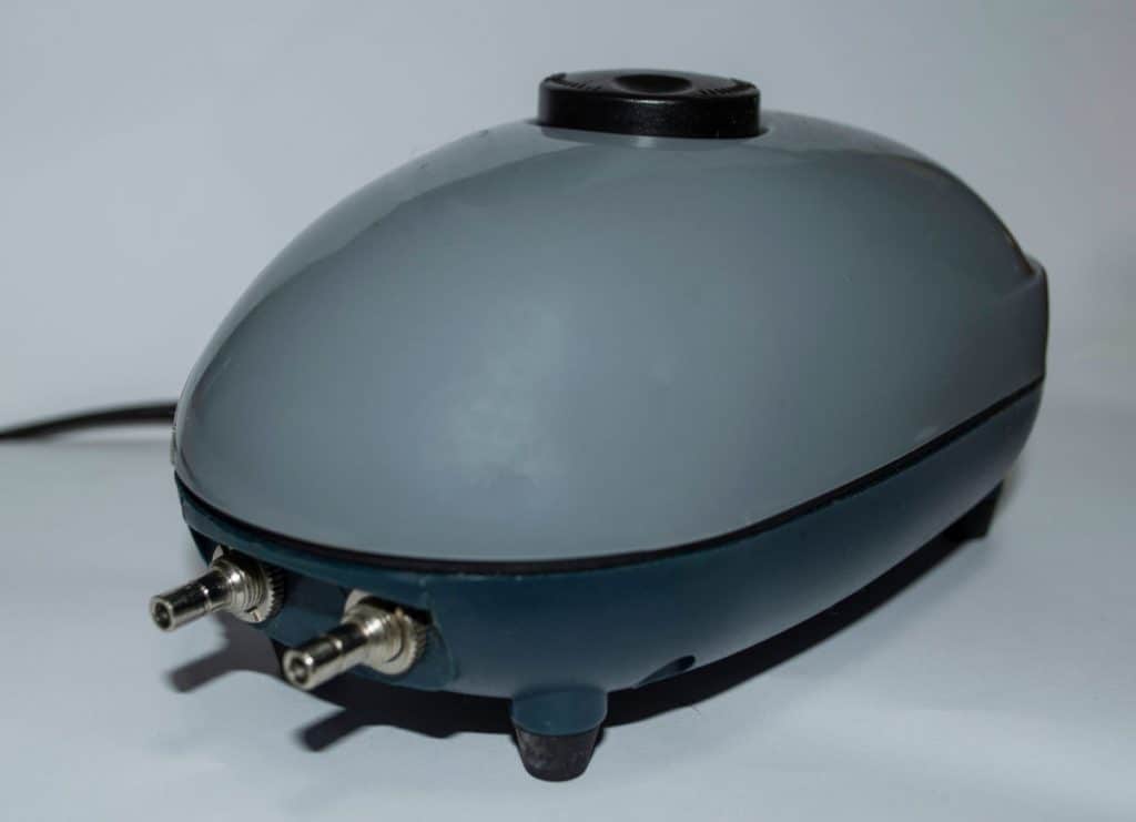 A grey aquarium air pump sitting on a white surface